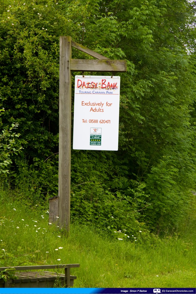 The sign is visible from the east, but approach from the west it's hidden behind some overhanging branches